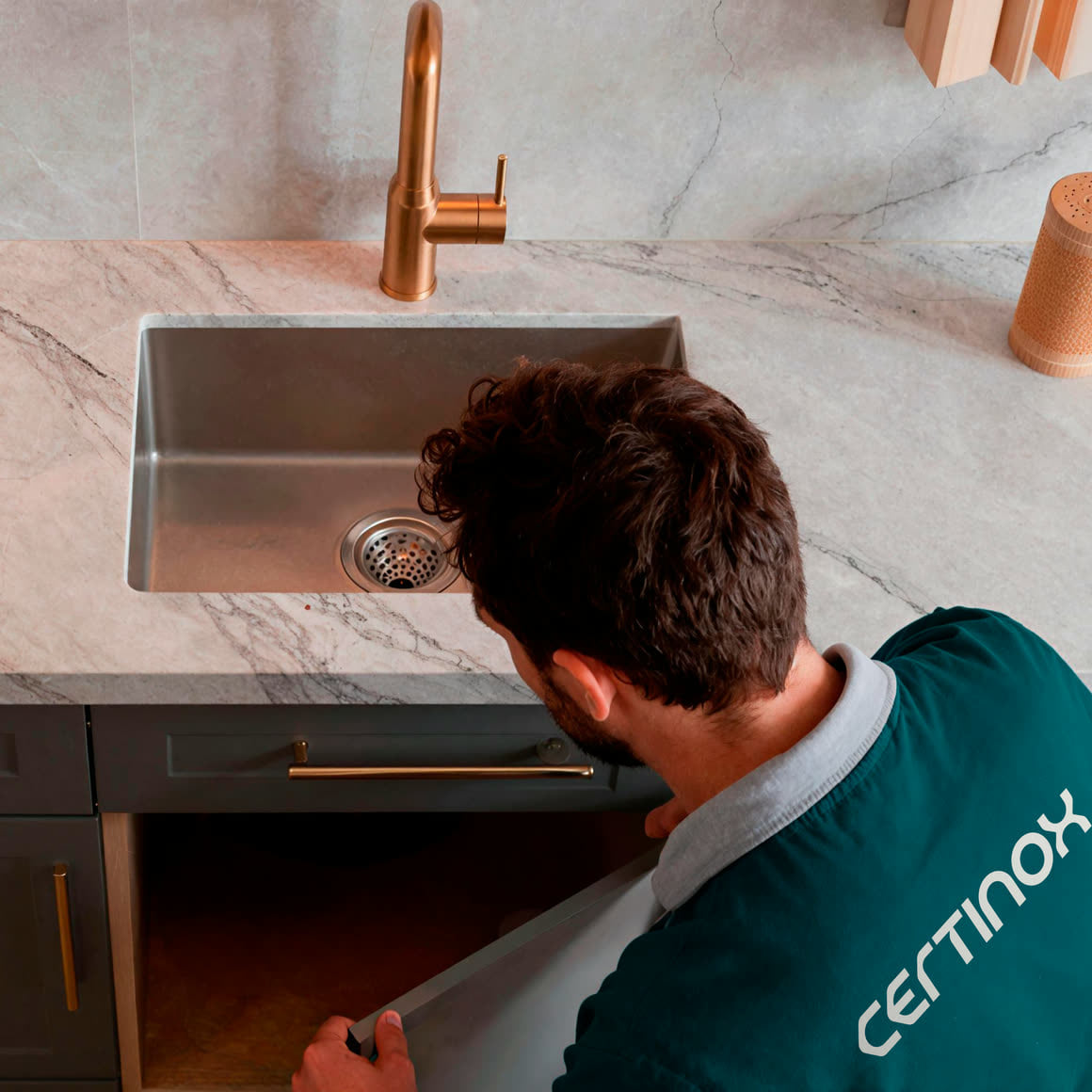 Certinox installer checking the plumbing under a marble countertop sink
