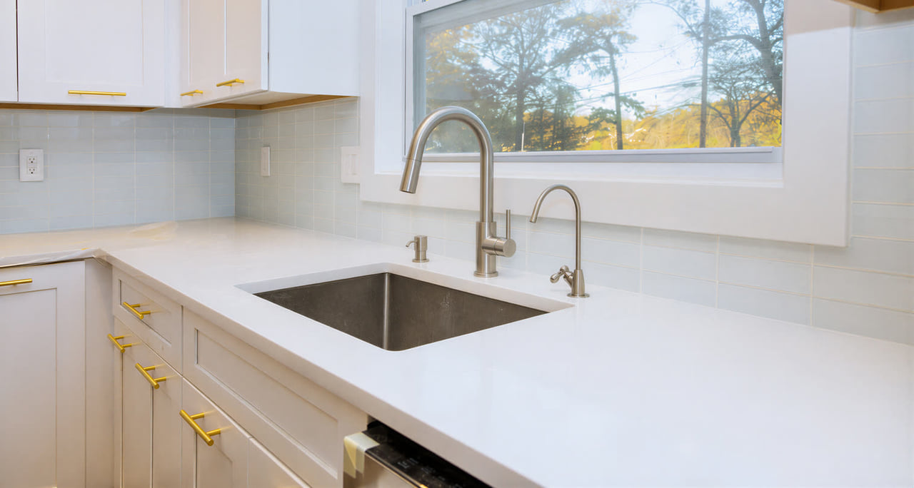 White quartz countertop with an undermount sink under a window
